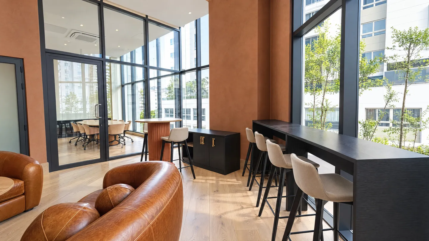 Área de coworking con barra alta frente a ventanales